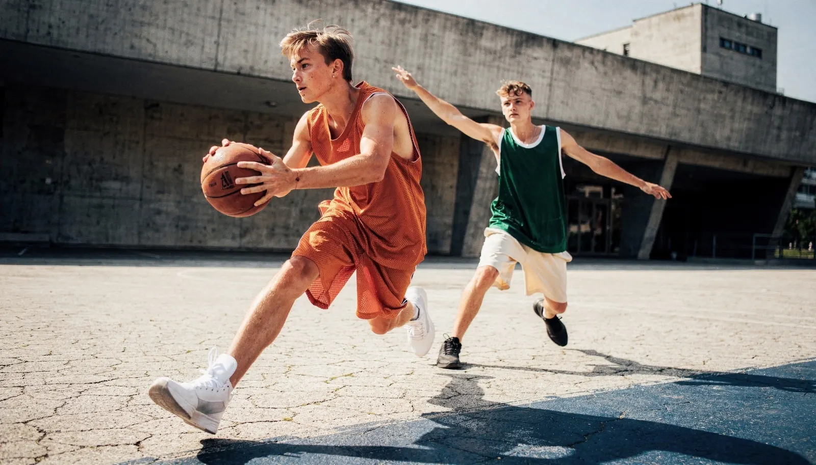 Two young athletes mid-stride on a sunlit track
