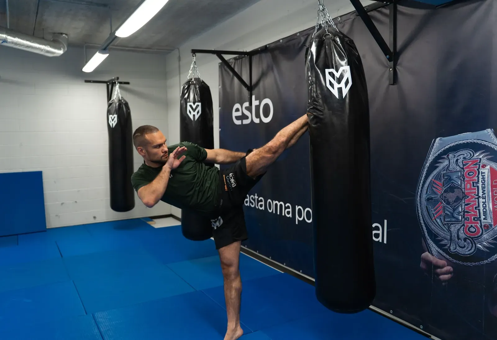 Max Vorovski landing a high kick on a heavy bag at his gym